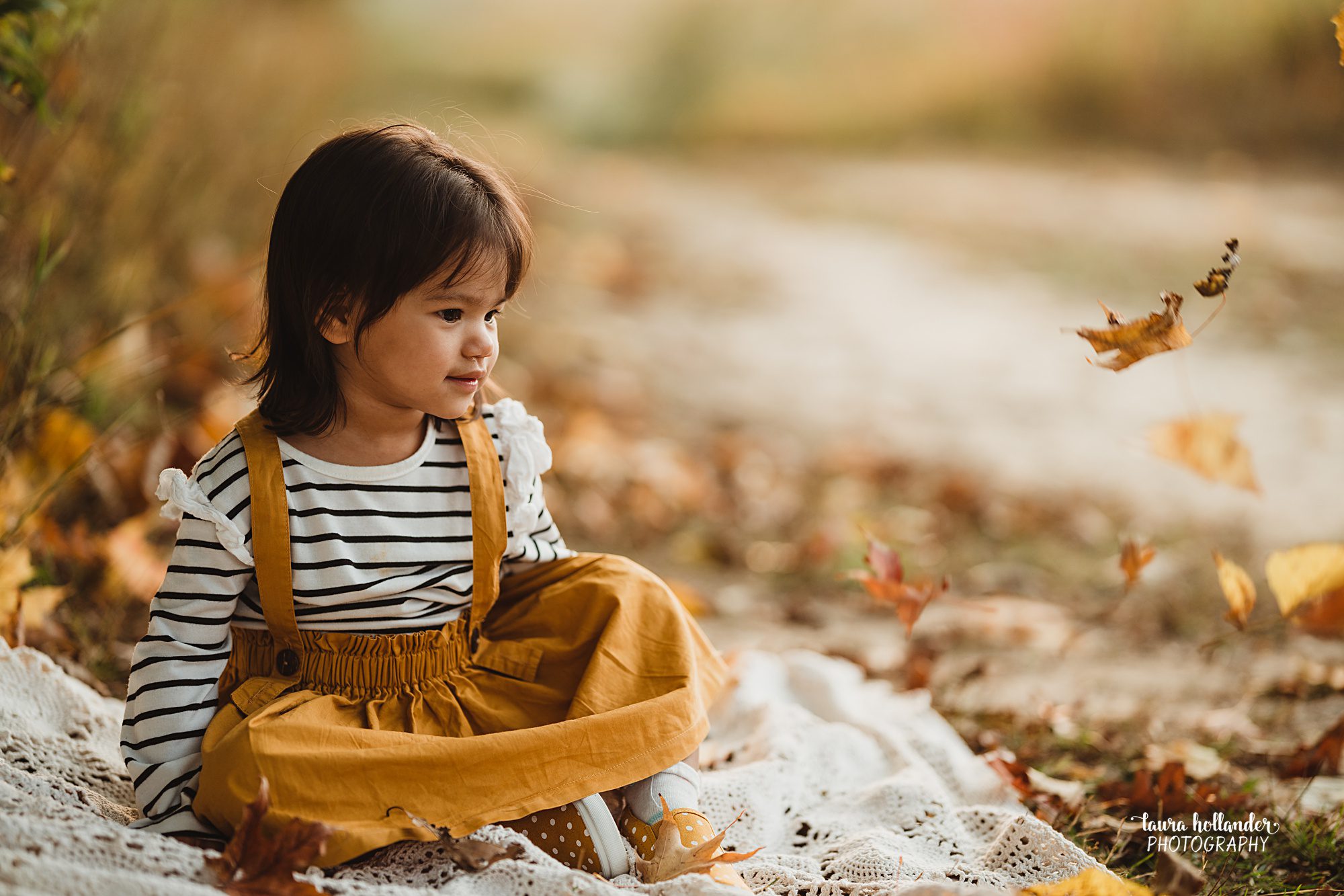 little girl with blowing fall leaves